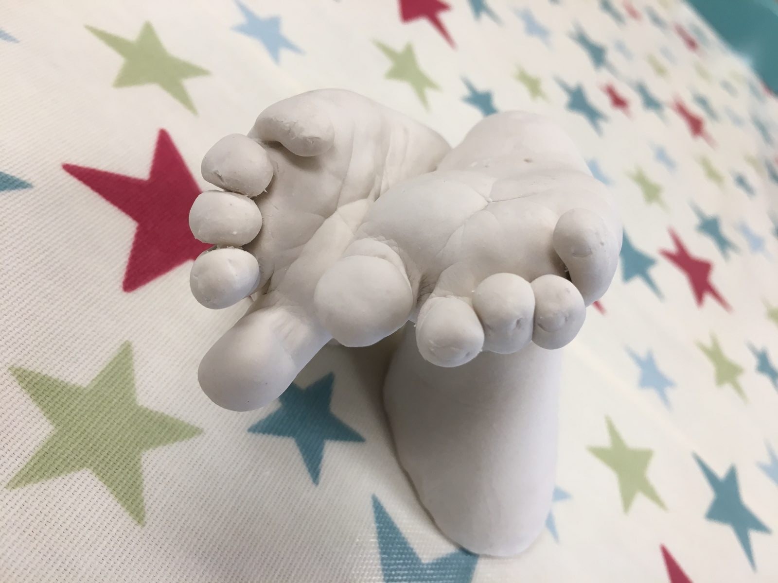 White cast of crossed baby feet on star fabric